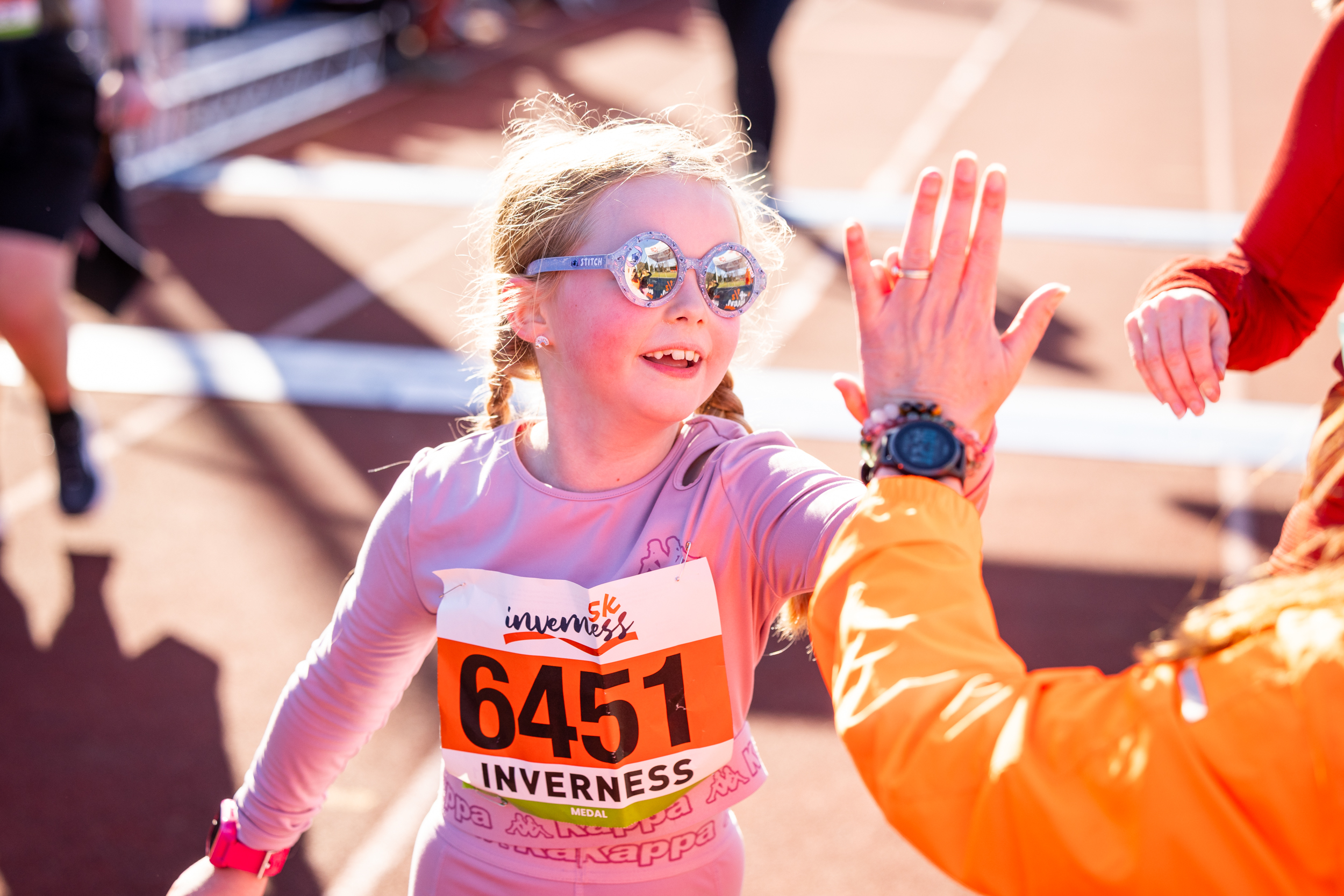 Child high fives one of the Inverness 5K staff 