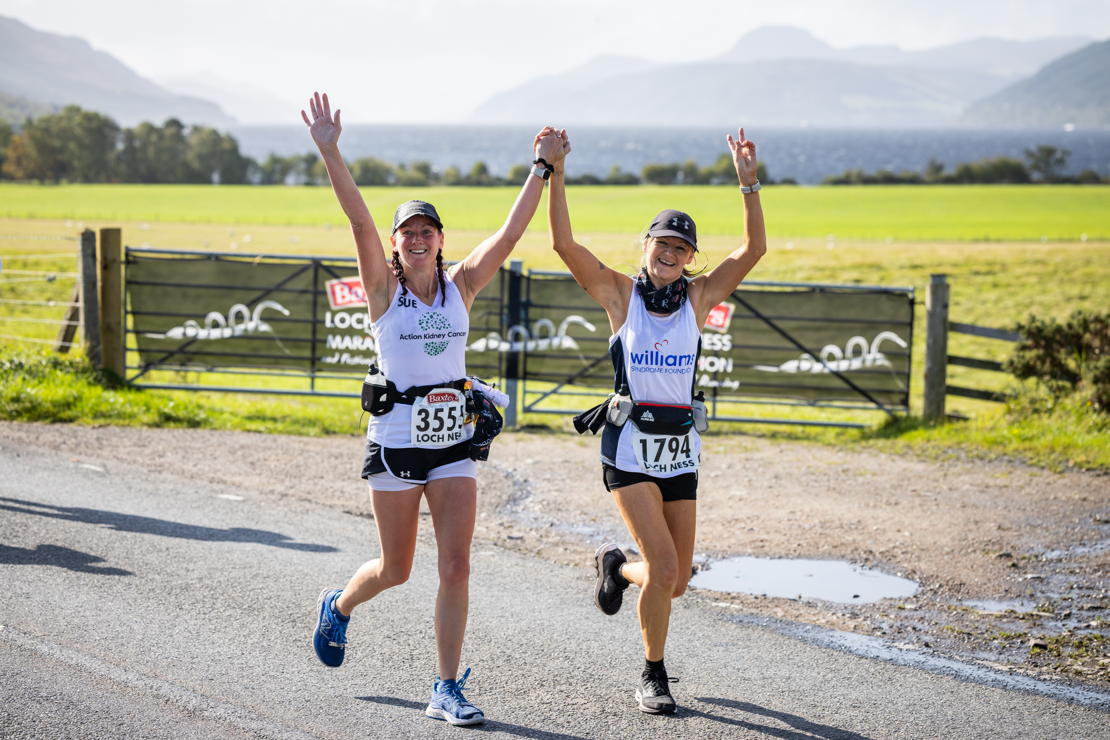 Charity runner pass a photographer with their hands in the air